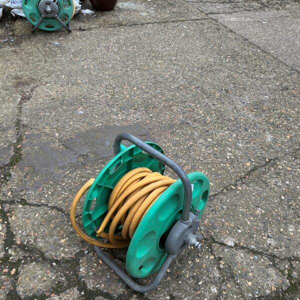 Green plastic garden hose reel for outdoor watering.