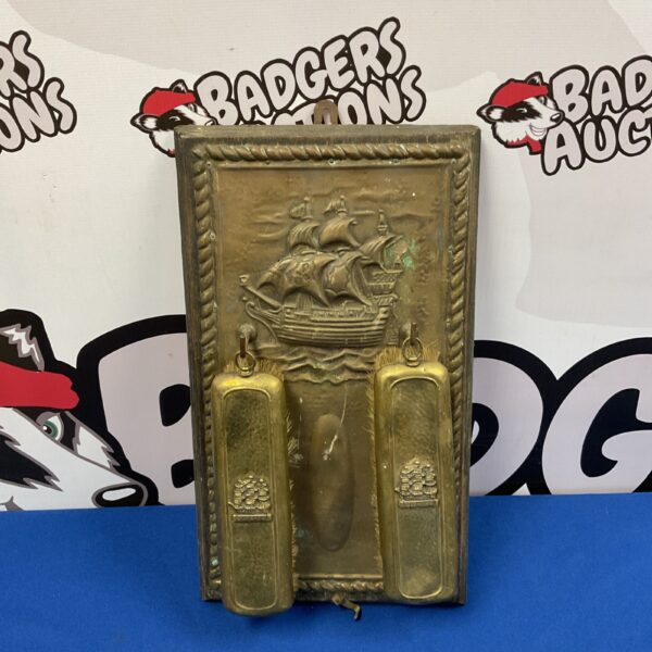 Vintage HMS Victory brass clothes brushes on wall mount.