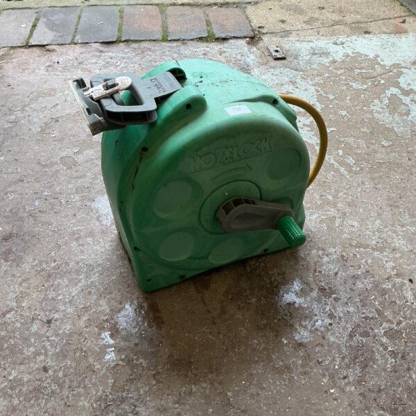 Green Hozlock garden hose reel for outdoor watering.