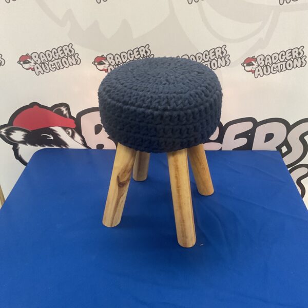 Neutral knitted footstool with wooden legs for home decor.