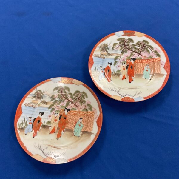 Pair of antique Kutani plates with vibrant hand-painted designs.