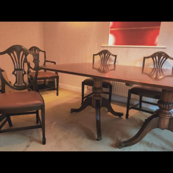 Large mahogany dining table with six leather chairs in a dining room.