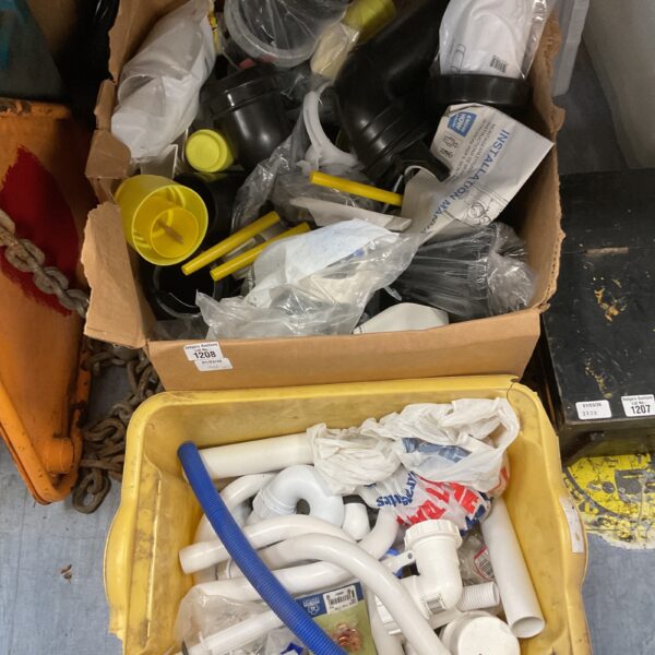 Assorted white PVC plumbing fittings in a yellow crate.