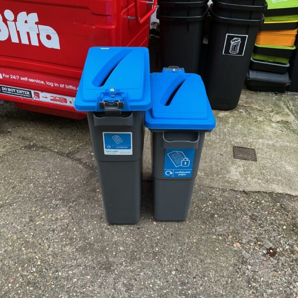 Blue and green recycling bins for outdoor waste management.