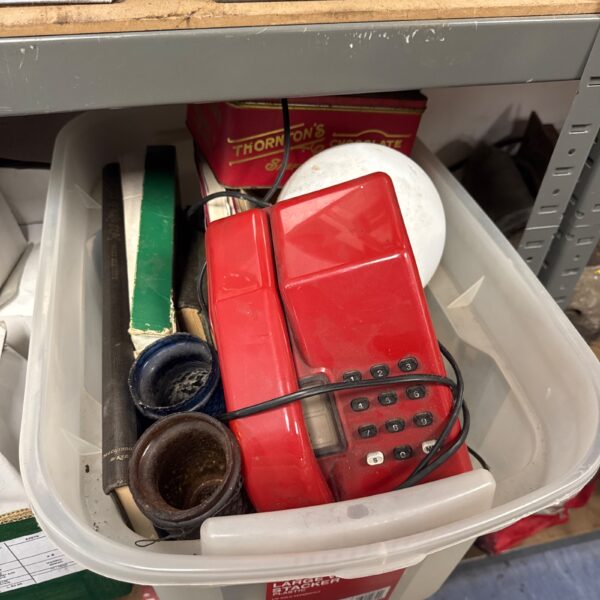Vintage red retro telephone amongst shed clearance items.