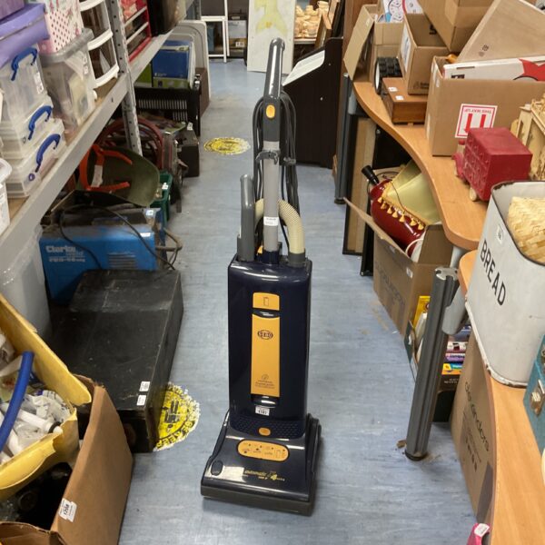 Used Sebo Automatic X4 vacuum cleaner in a cluttered room.