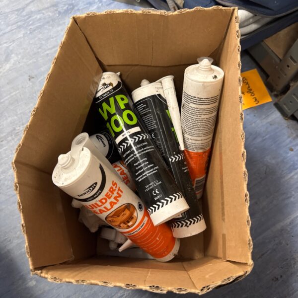Assorted new silicone sealant tubes in a cardboard box.