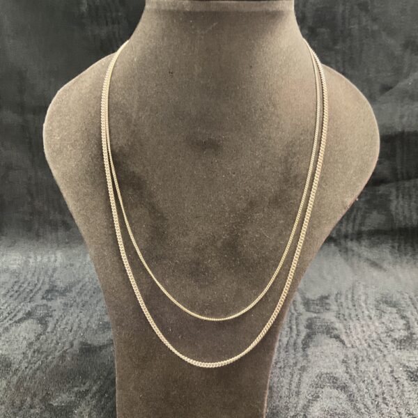 Two delicate 925 silver chain necklaces on a display bust.