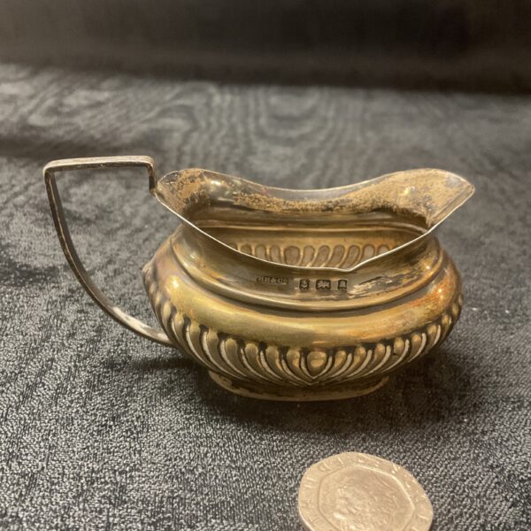 Hallmarked silver cream jug with embossed detailing.