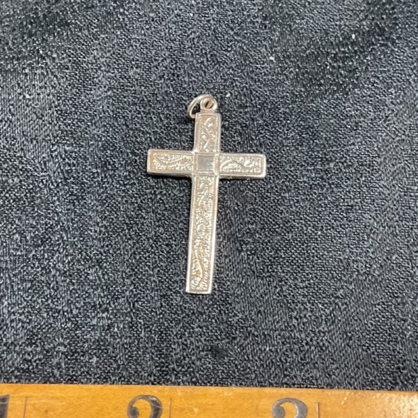 Detailed silver cross pendant with intricate relief work.