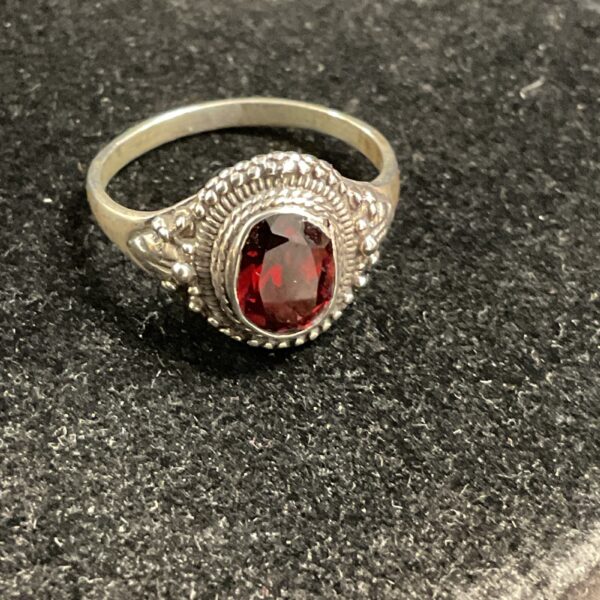 Close-up of a vintage silver ring with a vibrant garnet stone.