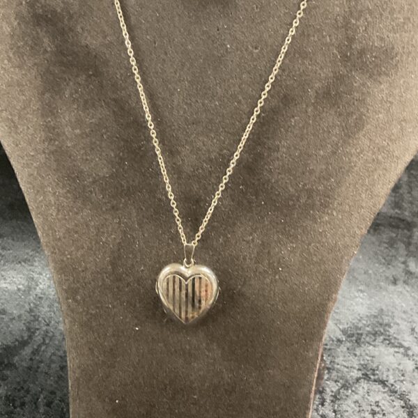 Silver heart locket necklace on a chain, vintage style.