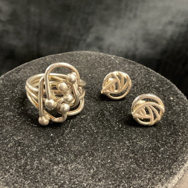 Close-up of silver ring and earrings set with flowing design.