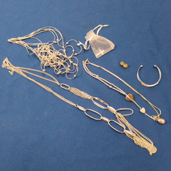 Silver tone jewellery lot including necklaces and a bangle.
