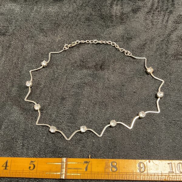 Silver tone wavy choker necklace with white stones.