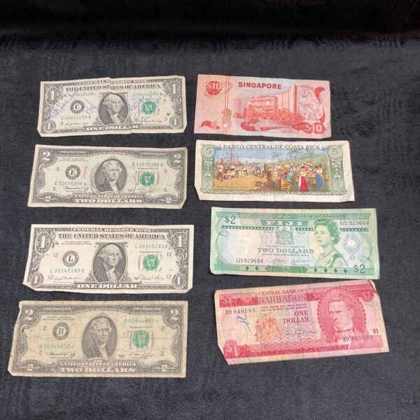 Collection of overseas banknotes including Singapore and Barbados currency.