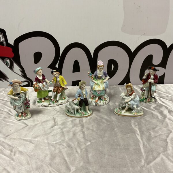 Group of antique Sitzendorf porcelain shepherd figurines on a white surface.