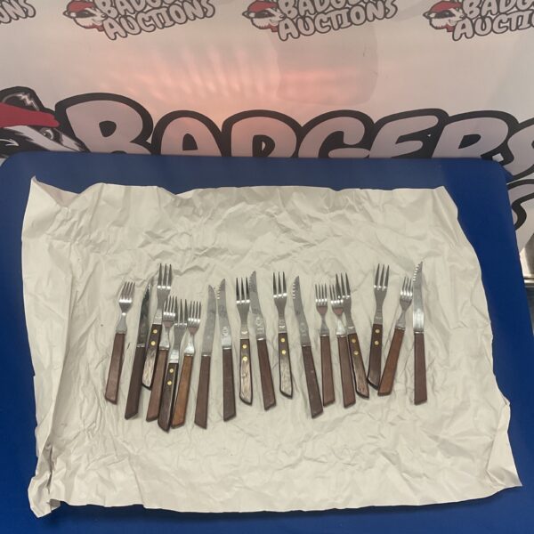 Stainless steel knives and forks cutlery set on a dark surface.