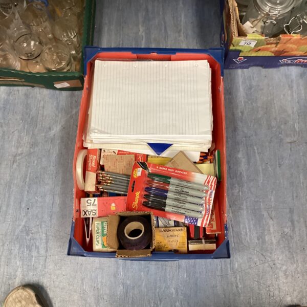 Tray of mixed stationery including note pads and pens.