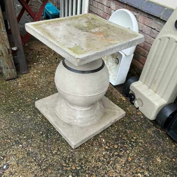 Tiered stone garden table in a garden setting.