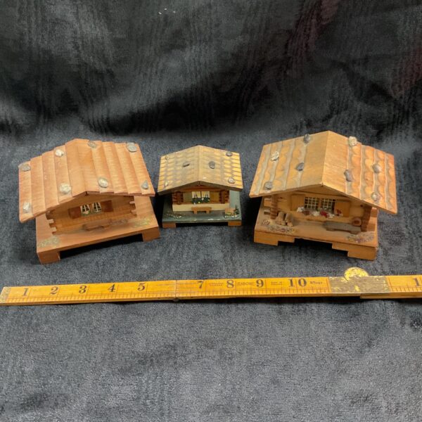 Vintage Swiss chalet music boxes and trinket pot set on display.