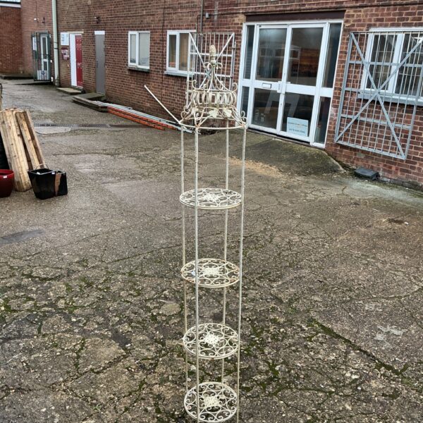 Vintage metal plant stand with tiered levels for displaying plants.