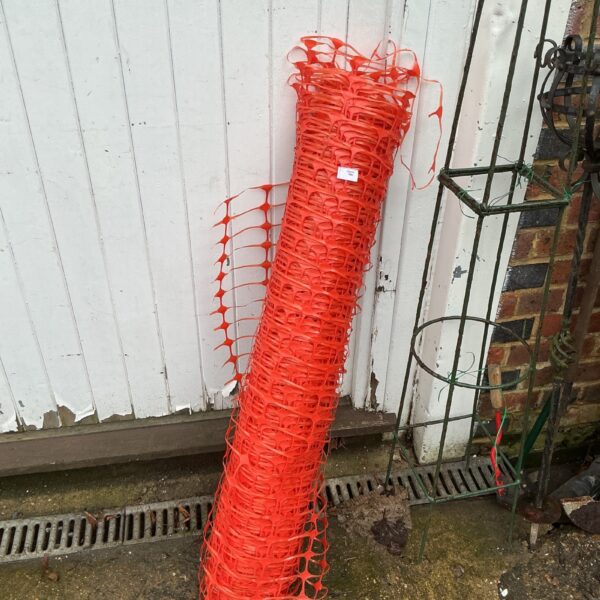 Bright orange roll of temporary fencing for site safety.