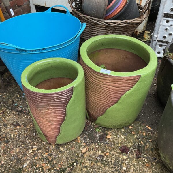 Two ribbed terracotta garden planters displayed outdoors.