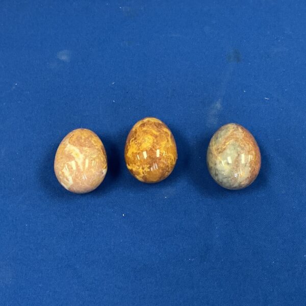 Three polished onyx eggs displayed on a dark surface.