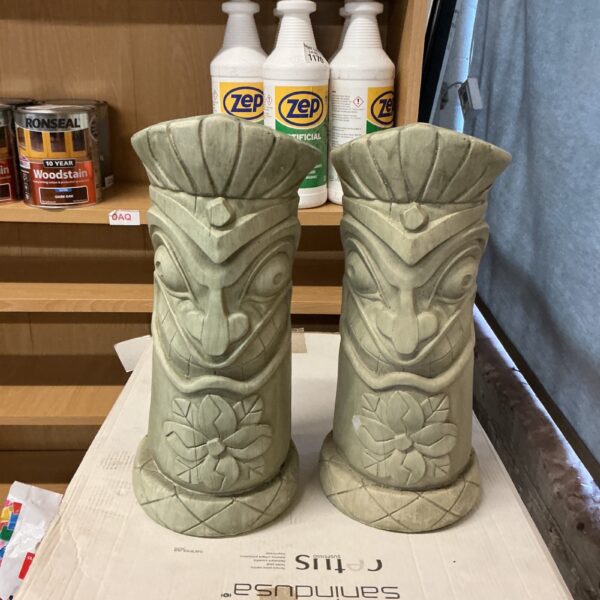 Vintage tiki totem figurines in a garden setting.