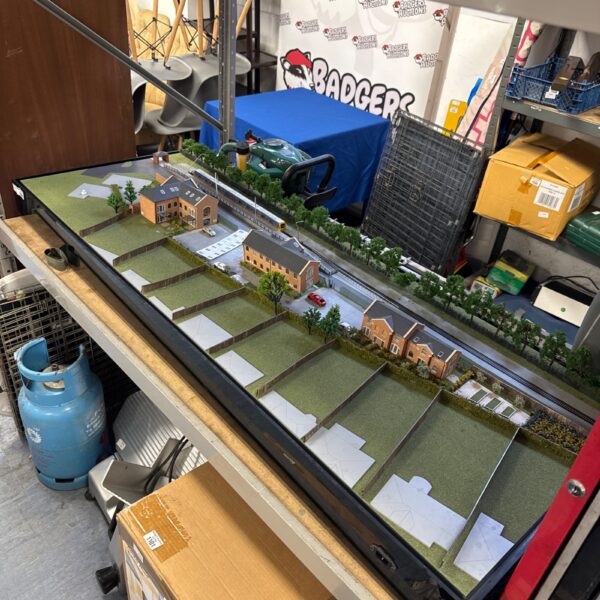 Detailed train track diorama with buildings and landscape.