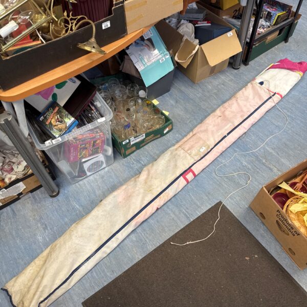 Full view of a vintage boat sail with canvas bag.