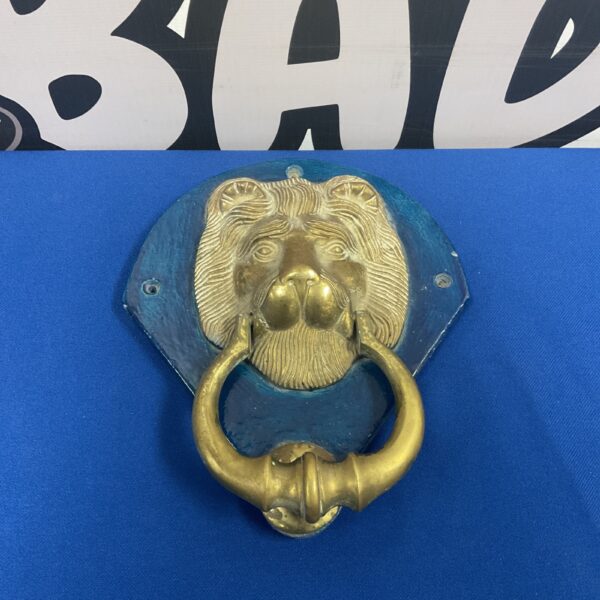 Vintage brass lion head door knocker on ceramic panel.