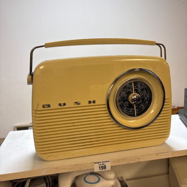 Cream coloured vintage Bush radio on a white surface.