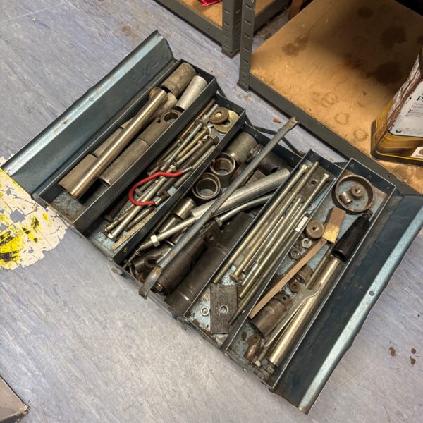 Vintage metal cantilever toolbox filled with various tools.