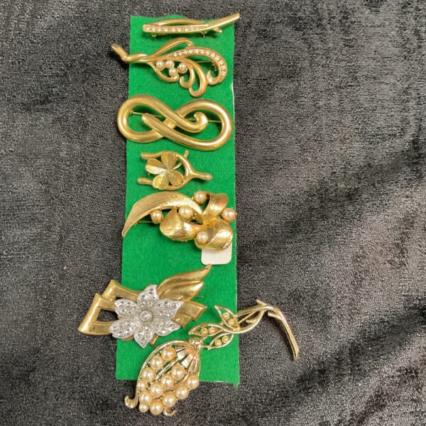 Vintage costume brooch lot featuring gold plated pins and floral designs.