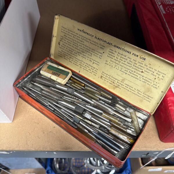 Vintage first aid kit tin with assorted medical taps and dressings.