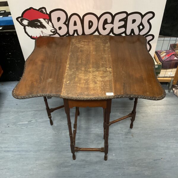 Vintage wooden gate leg table with drop leaf design.
