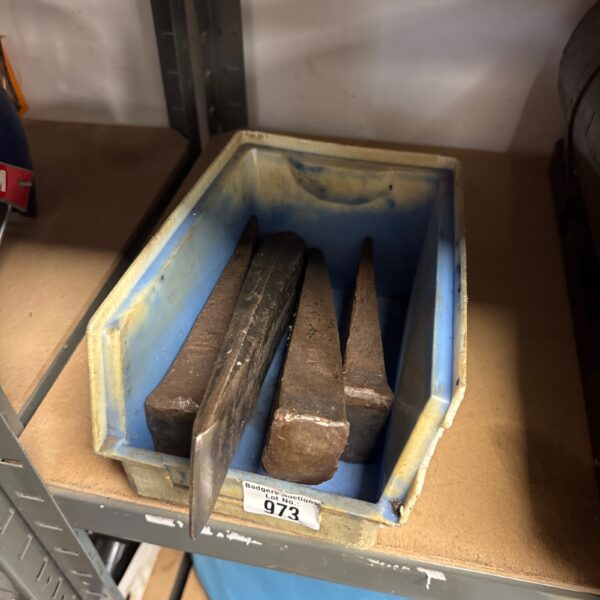 Four vintage log splitting spikes in a plastic container.