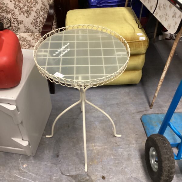 Vintage metal garden table with glass top and tripod base.