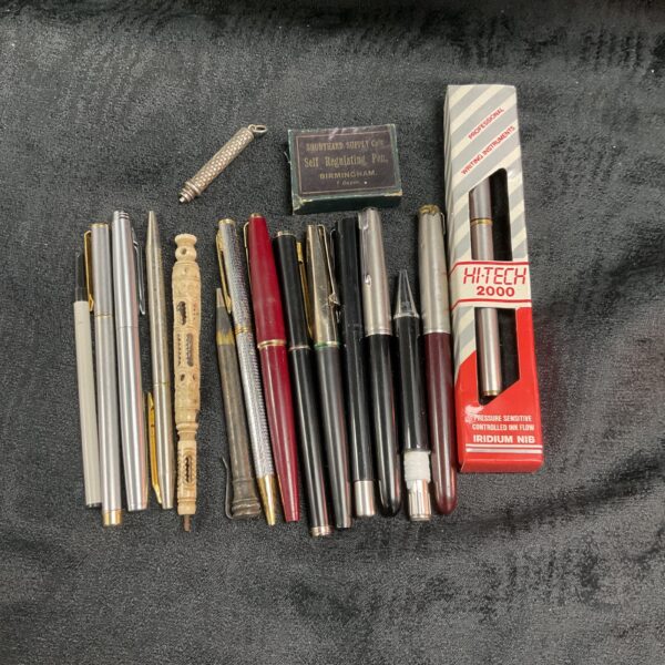 Vintage pen tray with assorted collectible writing instruments.