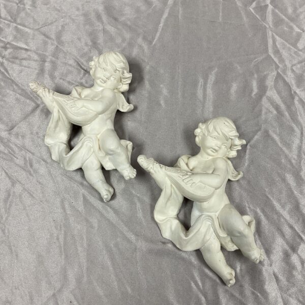Pair of vintage plaster cherubs on a silver background.