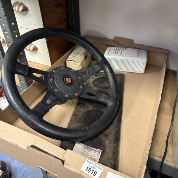 Vintage Porsche steering wheel with crest, classic car part.