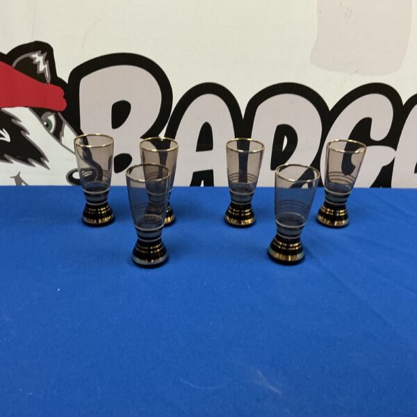Set of six vintage shot glasses with decorative bands.