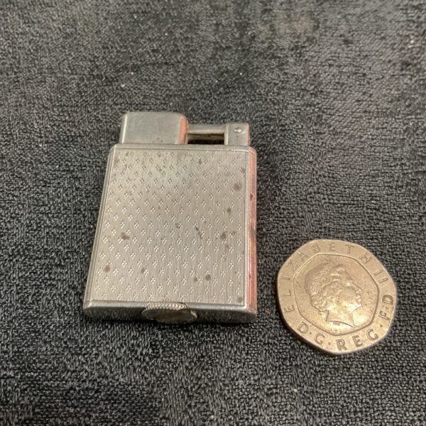 Vintage silver petrol lighter with geometric pattern.