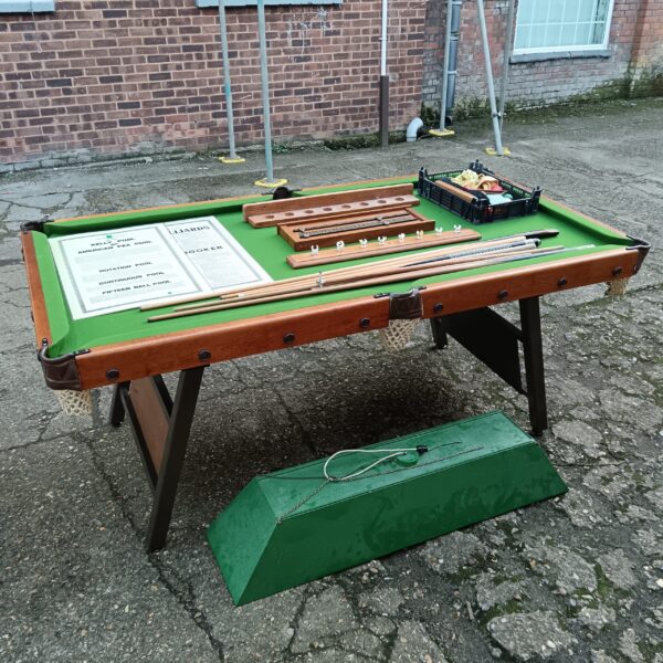 Vintage snooker table with accessories in a games room setting.