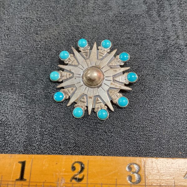 Close-up of vintage Taxco silver brooch with turquoise stones.