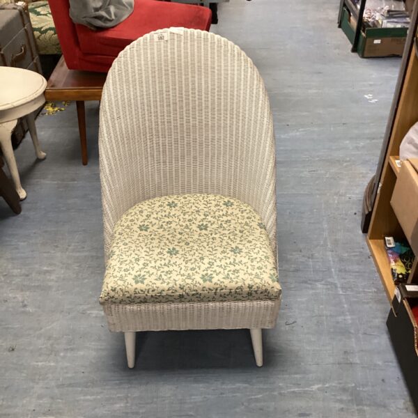 Vintage wicker bedroom chair with floral upholstery and curved back.