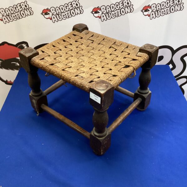Vintage woven footstool with a rustic wooden frame and woven seat.