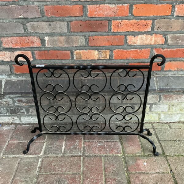 Vintage wrought iron fire screen with ornate scrolling design.